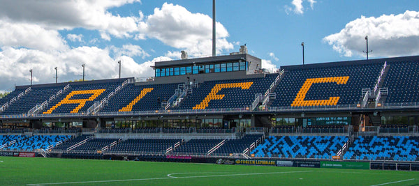 Stadium with blue seats and 'RIFC' branding on a cloudy day